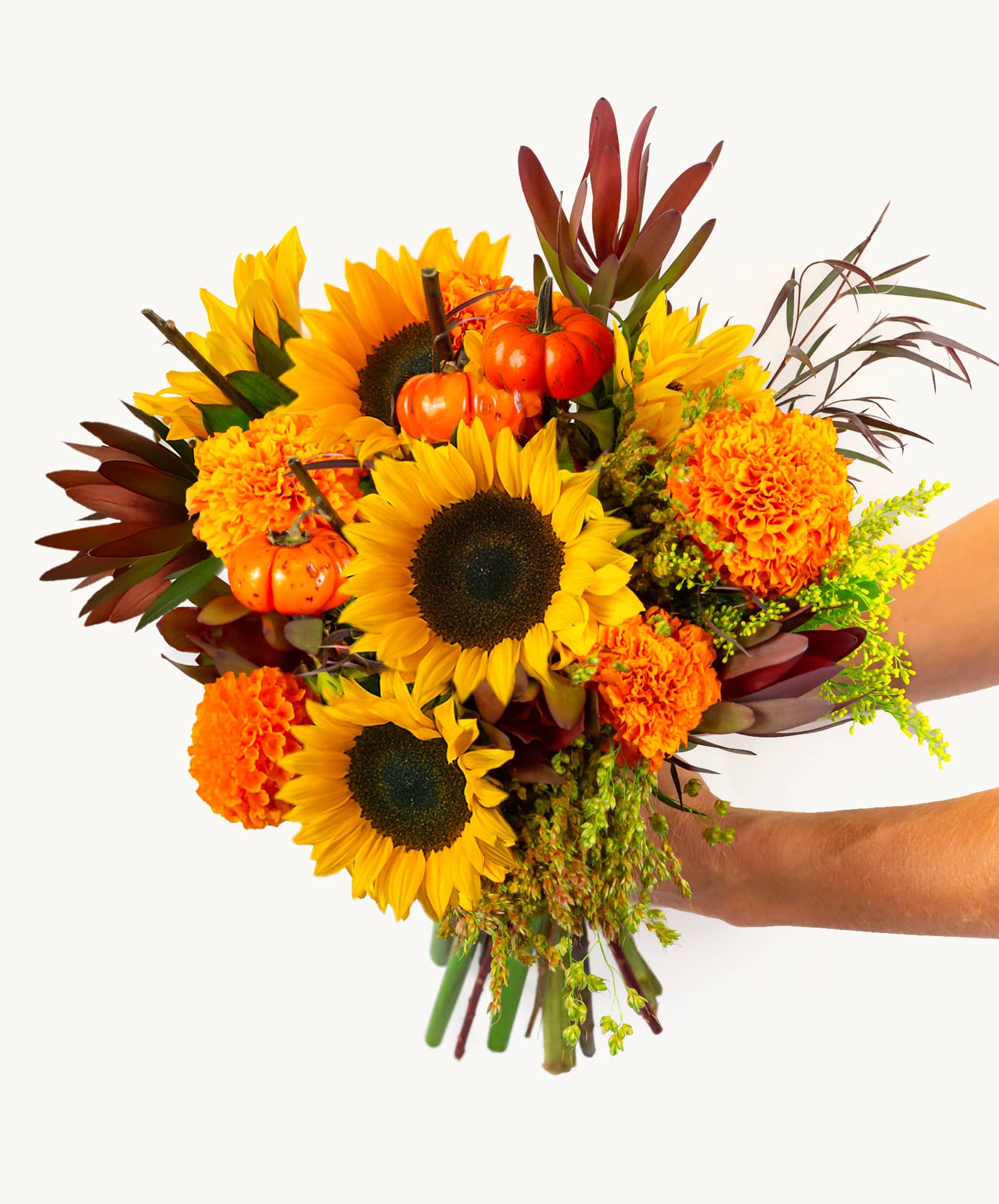 Vibrant floral bouquet featuring sunflowers, marigolds, and miniature pumpkins in autumn hues.