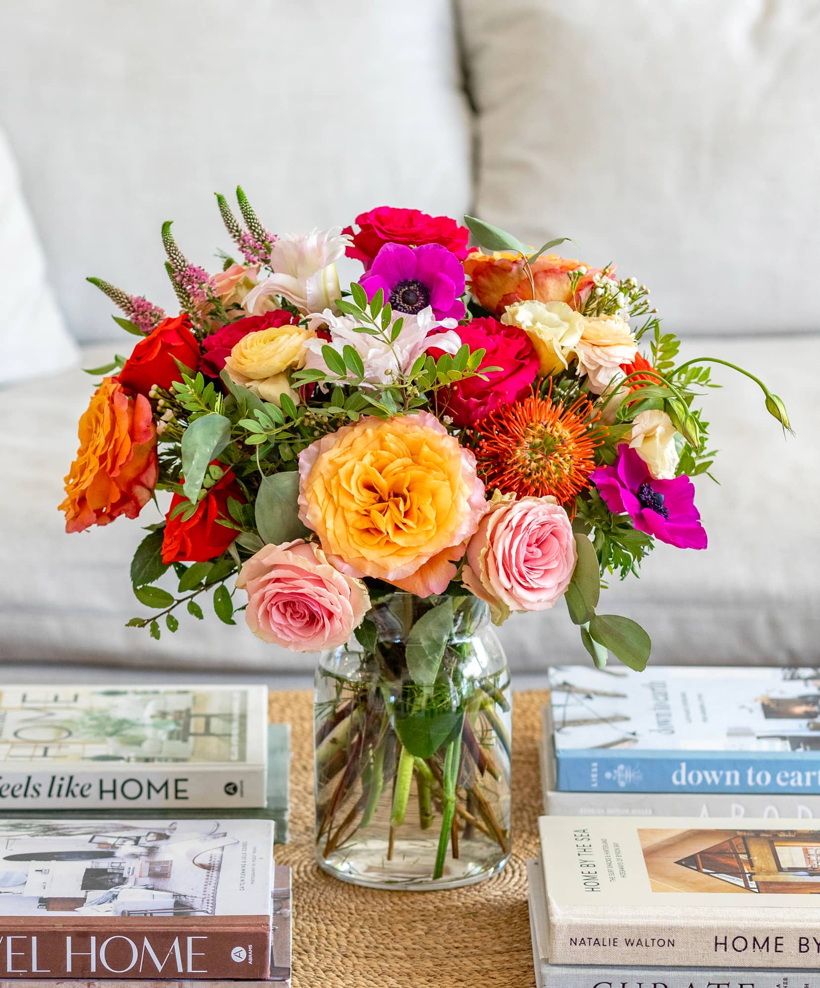 Vibrant floral arrangement featuring roses, anemones, and seasonal blooms in a clear vase.